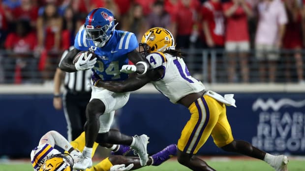 Sep 30, 2023; Oxford, Mississippi, USA; Mississippi Rebels running back Ulysses Bentley IV (24) runs the ball as Tigers linebacker Harold Perkins Jr. (4) and defensive back Andre' Sam (14) make the tackle during the second half at Vaught-Hemingway Stadium. Mandatory Credit: Petre Thomas-USA TODAY Sports